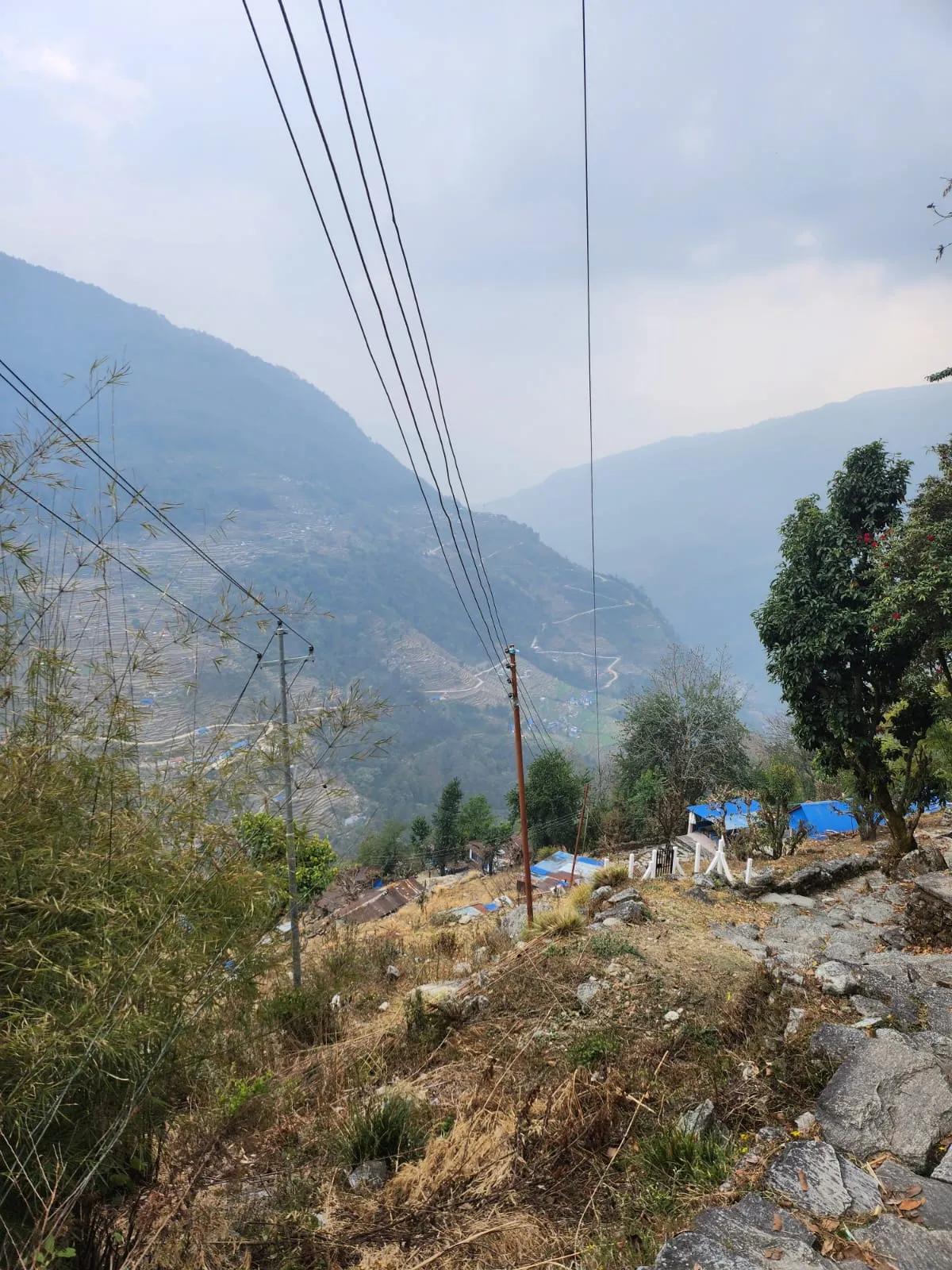 View down into the Annapurna foothills valley from the Ulleri trail showing terraced fields and a winding mountain road, Nepal